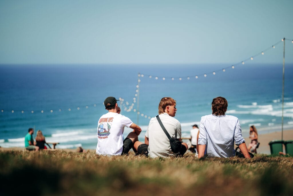 WILL BAILEY FRIDAY DROP 1 008 Boardmasters people sat on grass looking at beach